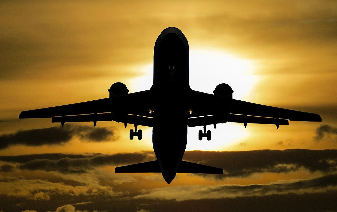 Aircraft silhouette flying into a sunset sky