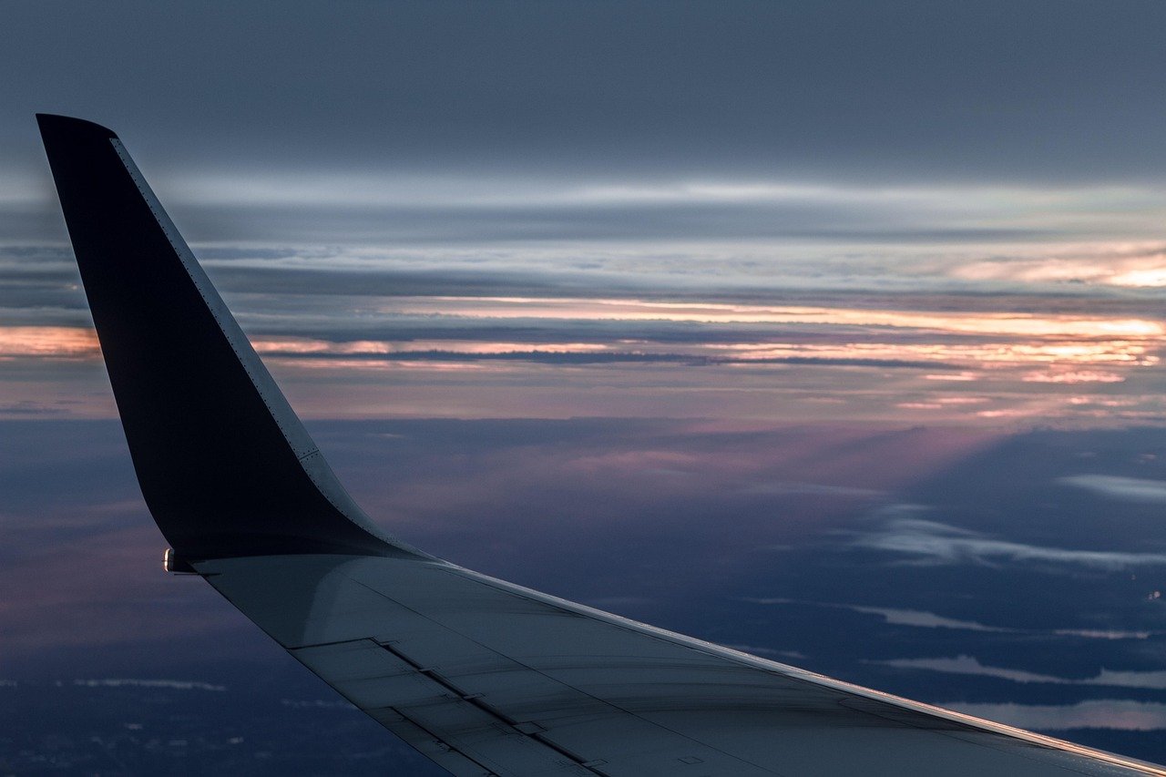 Airplane wing above clouds at sunset