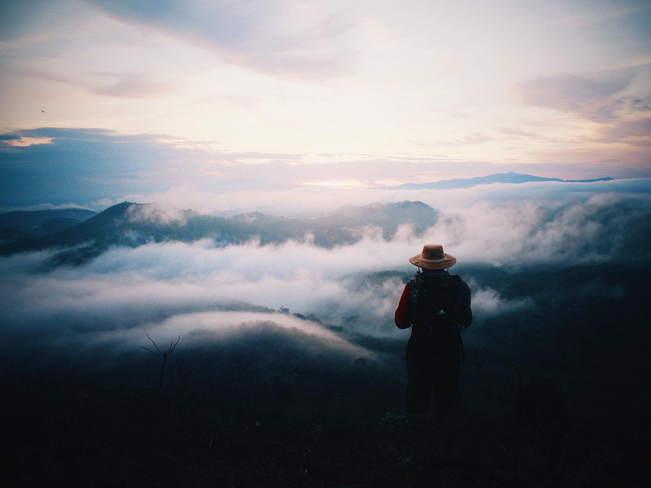 Solo traveler silhouette watching a sunset over mountains